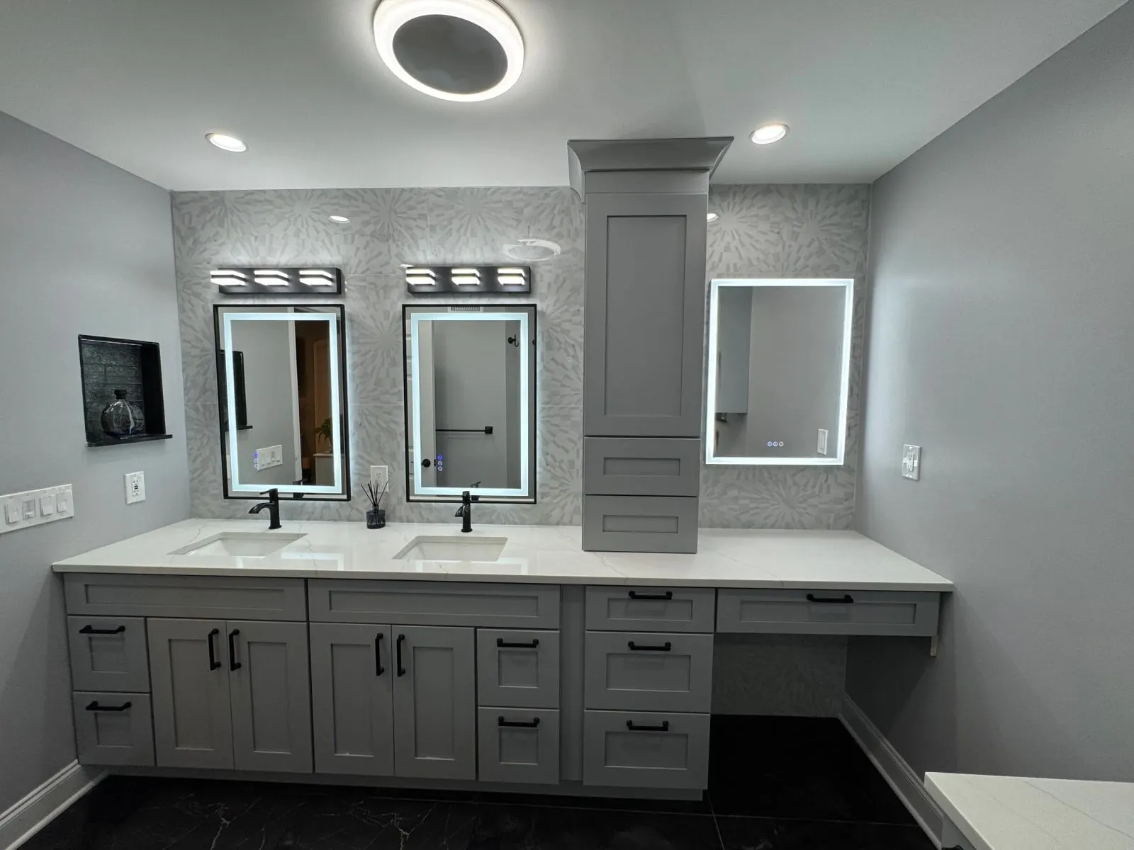 Vanity wall with lighted mirrors, two sinks and a tall linen cabinet